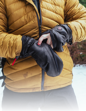 close up shot of hands wearing the Heattouch Hellfire Magne Mitt with a hand sticking out of one mitt pressing the heated button
