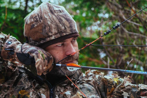 Hunter wearing cold weather gear while drawing his bow