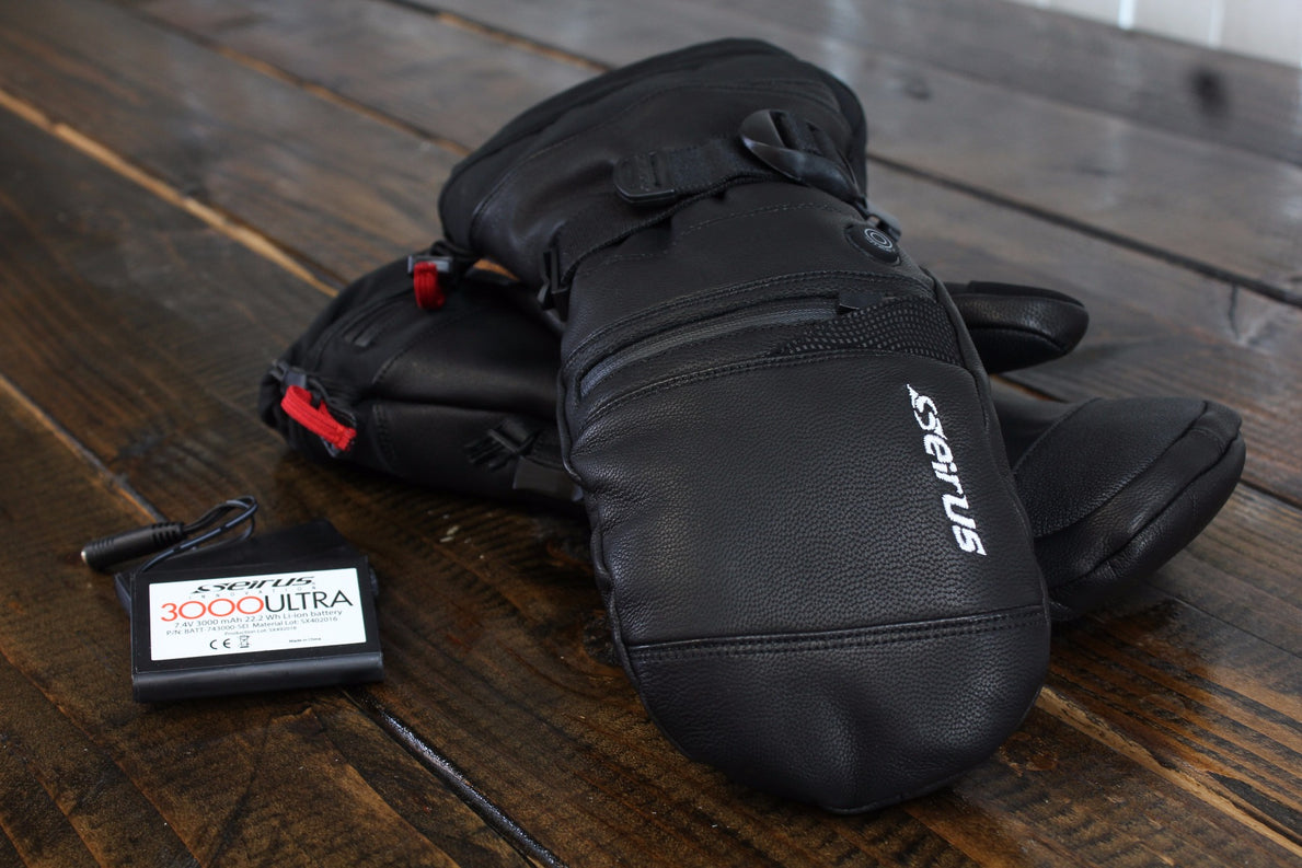 Image of two stacked heattouch hellfire mitts in black and separate battery on wooden table